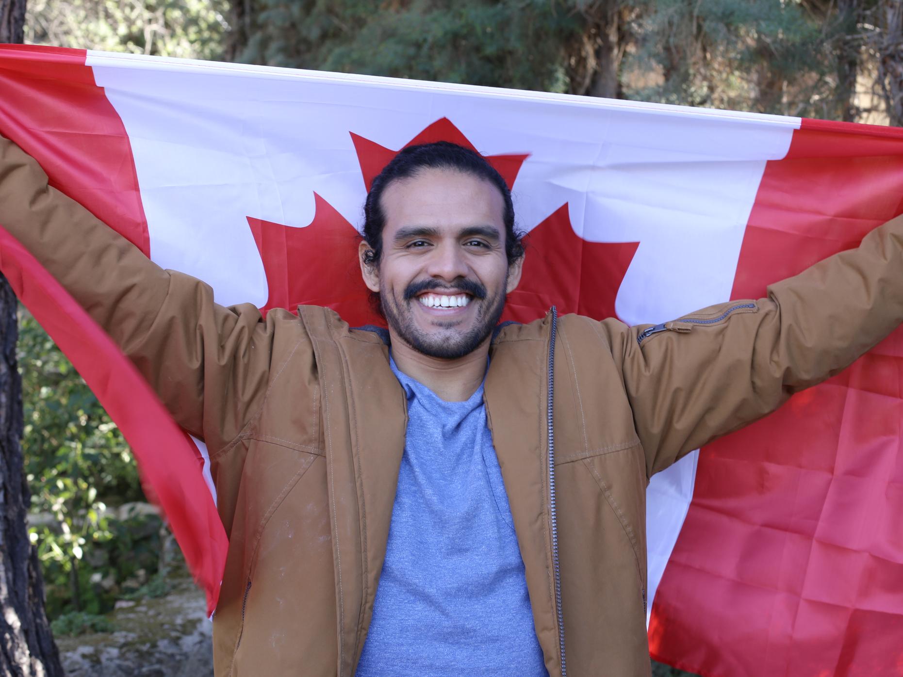 A new Canadian holding a Canadian flag and smiling