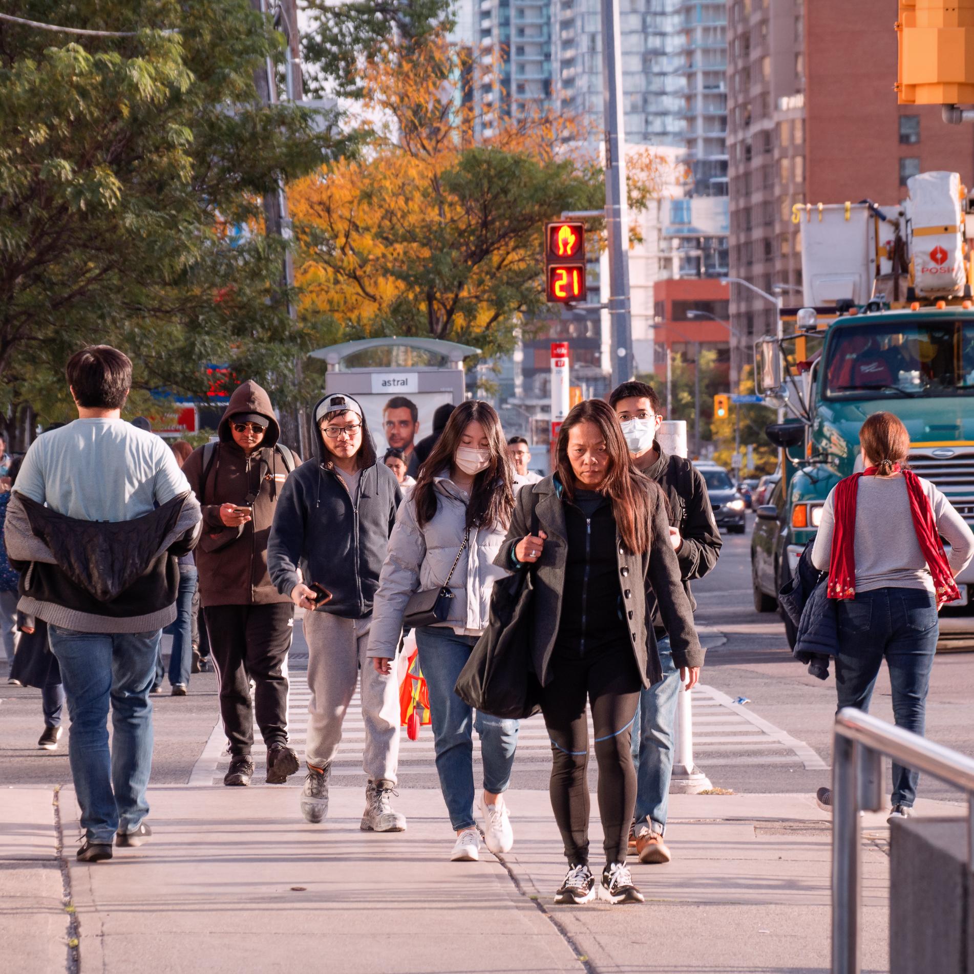 A crowd of people walking on the street in Toronto, on an early evening in 2022