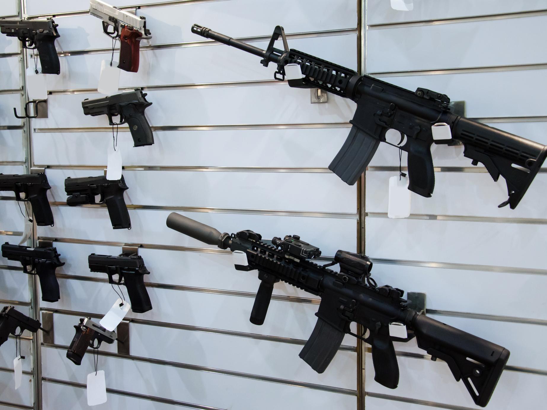 Guns hang on a wall in a gun store