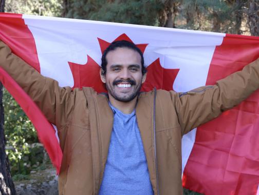 A new Canadian holding a Canadian flag and smiling