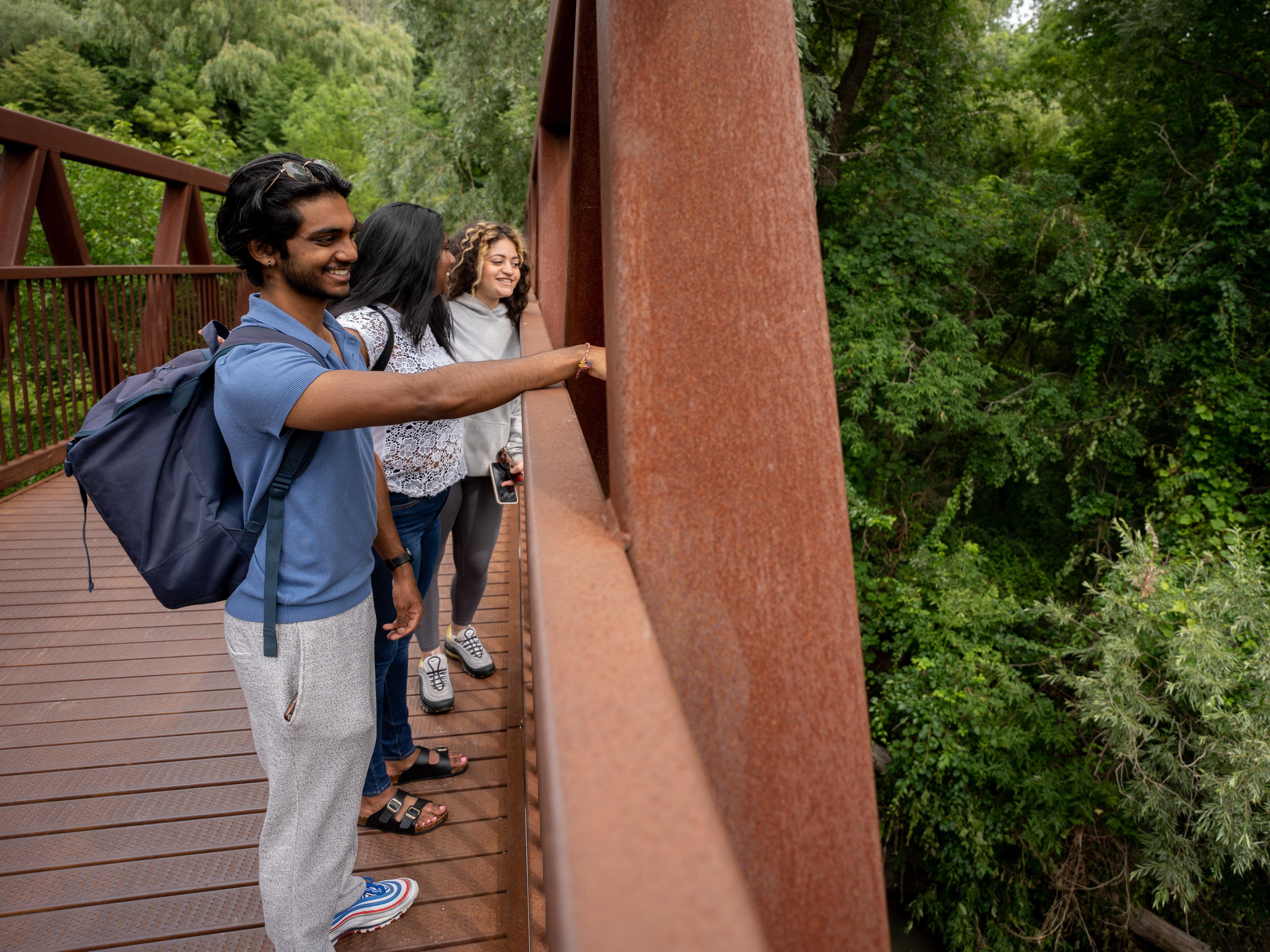 students on the bridge over Highland Creek in the valley with trees in background